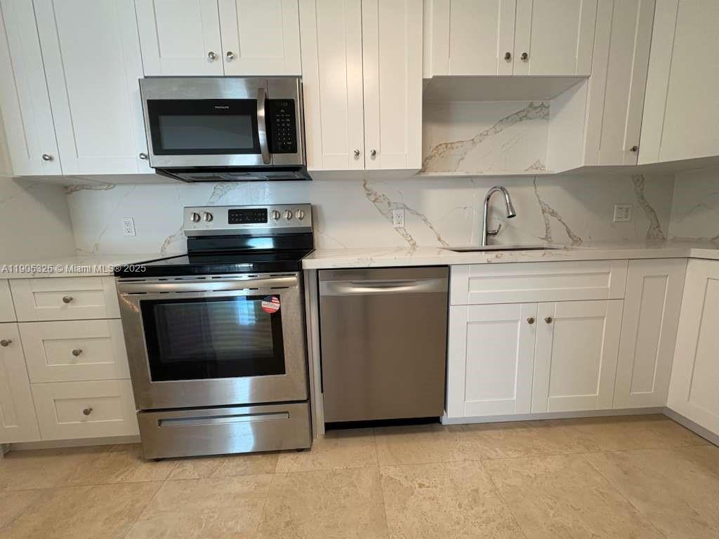 1627 Southwest 37th Avenue, Unit 207 Miami, FL 33145 - Photo 6 of 24 a kitchen with white cabinets and stainless steel appliances