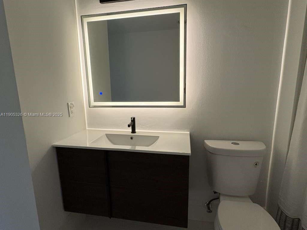 1627 Southwest 37th Avenue, Unit 207 Miami, FL 33145 - Photo 9 of 24 a bathroom with a toilet sink and mirror