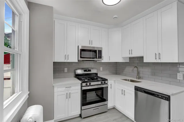 a kitchen with white cabinets and appliances