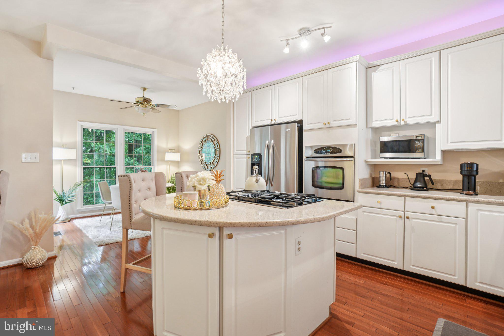 11742 Valley Ridge Circle Fairfax, VA 22033 - Photo 8 of 34 a kitchen with stainless steel appliances kitchen island granite countertop a stove a sink dishwasher a dining table and chairs with wooden floor
