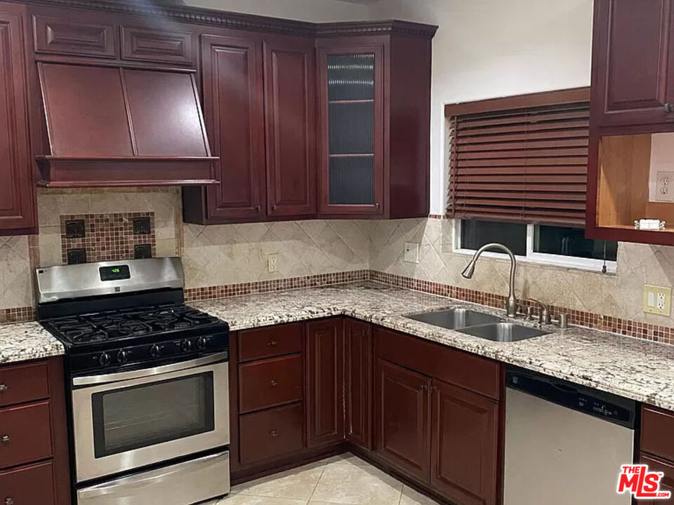 a kitchen with granite countertop a sink a stove and cabinets