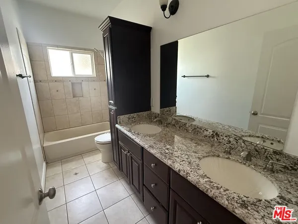 a bathroom with a granite countertop sink a toilet and shower