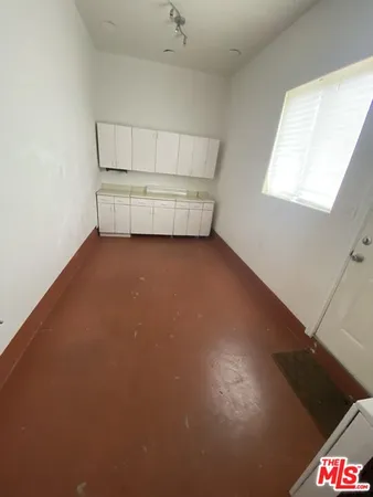 an empty room with cabinet and windows