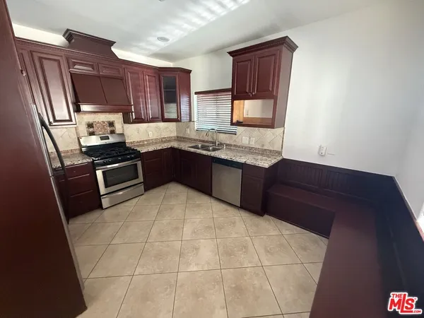 a kitchen with stainless steel appliances granite countertop wooden cabinets a stove top oven a sink and dishwasher