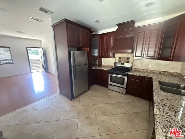 a kitchen with granite countertop a refrigerator and a stove top oven
