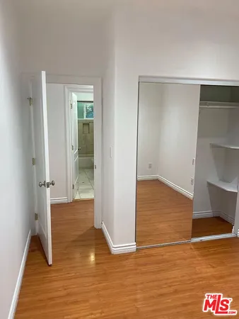 a view of an empty room with wooden floor and closet