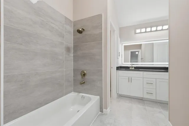 a bathroom with a bathtub sink vanity and mirror