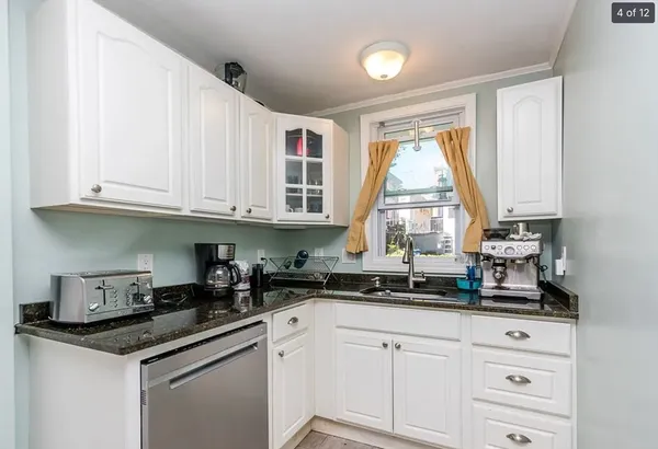 a kitchen with white cabinets and a window