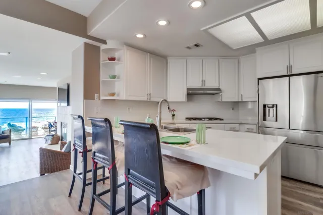 a kitchen with stainless steel appliances granite countertop a stove a refrigerator a sink a dining table and chairs with wooden floor