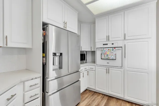 a kitchen with cabinets stainless steel appliances and wooden floor