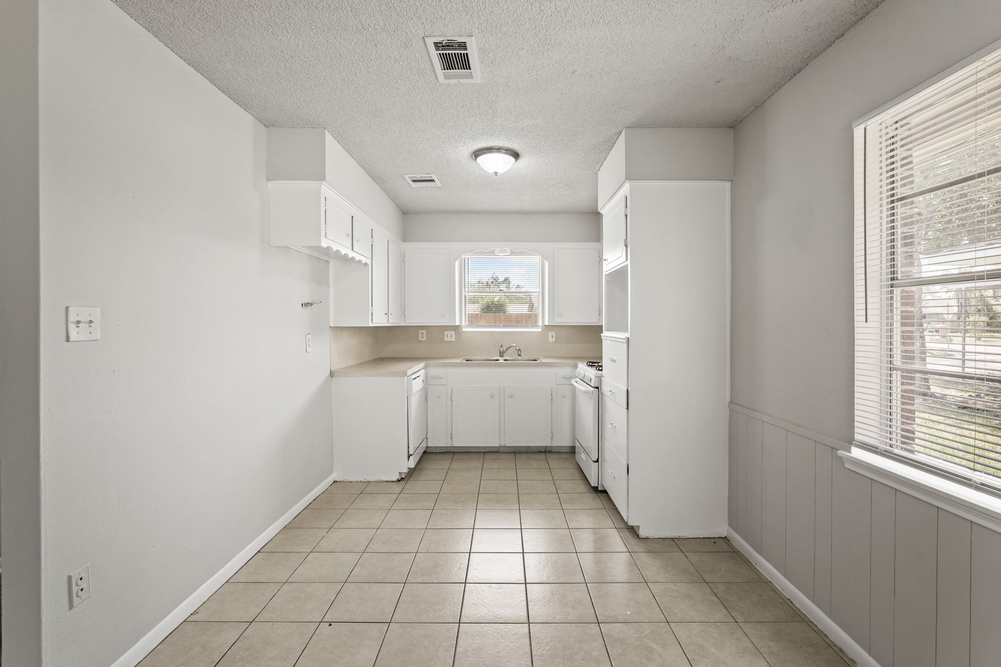 1802 Mosher Lane Houston, TX 77088 - Photo 11 of 18 a large white kitchen with a sink a refrigerator and window