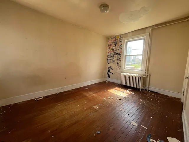 an empty room with wooden floor and windows