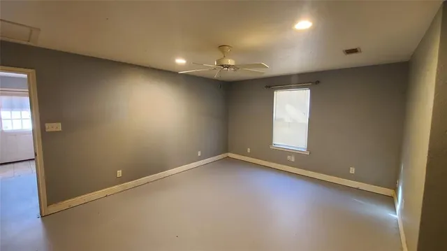 an empty room with a window and ceiling fan