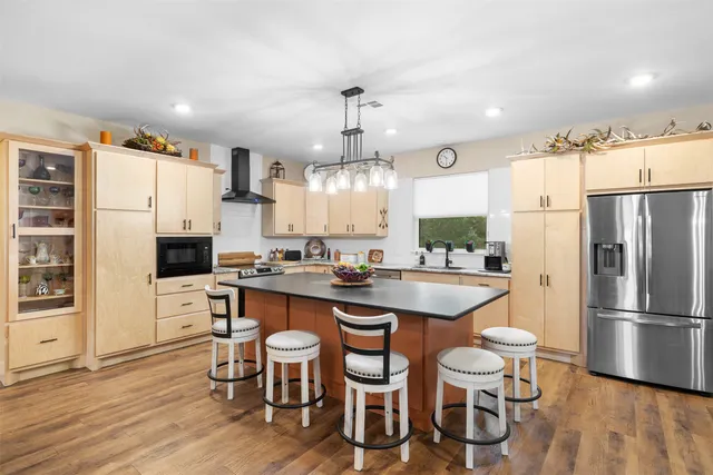 a kitchen with stainless steel appliances a dining table chairs refrigerator and sink