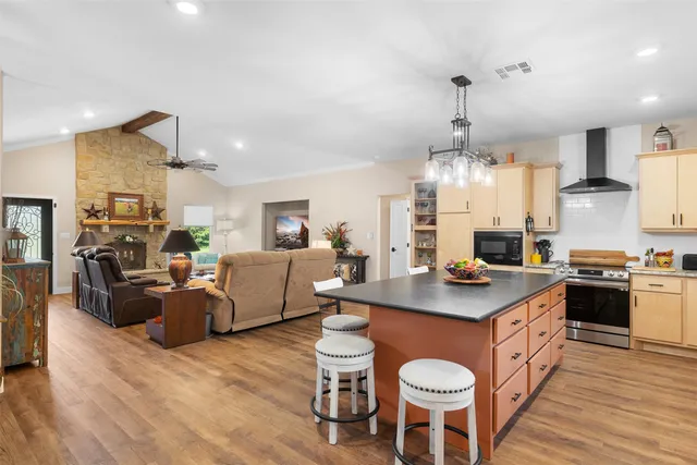 a kitchen with stainless steel appliances granite countertop a sink dishwasher a stove a dining table and chairs with wooden floor