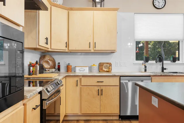a kitchen with stainless steel appliances granite countertop a sink and cabinets with wooden floor