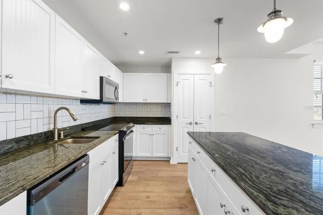 a kitchen with granite countertop stainless steel appliances sink stove and cabinets