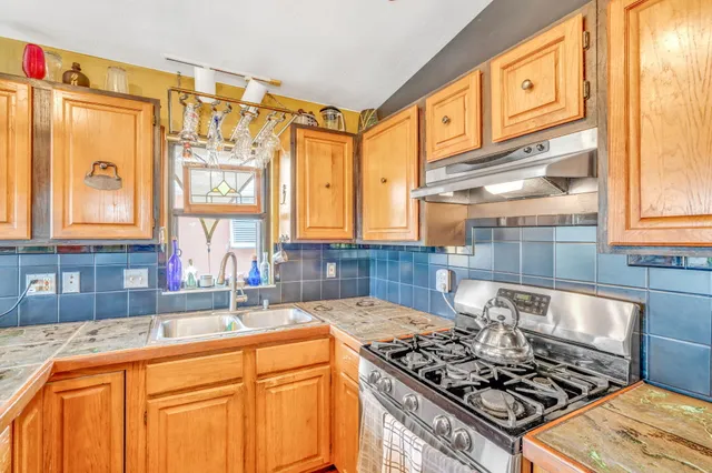 a view of a kitchen with granite countertop a sink and dishwasher a oven with a dining table and chairs