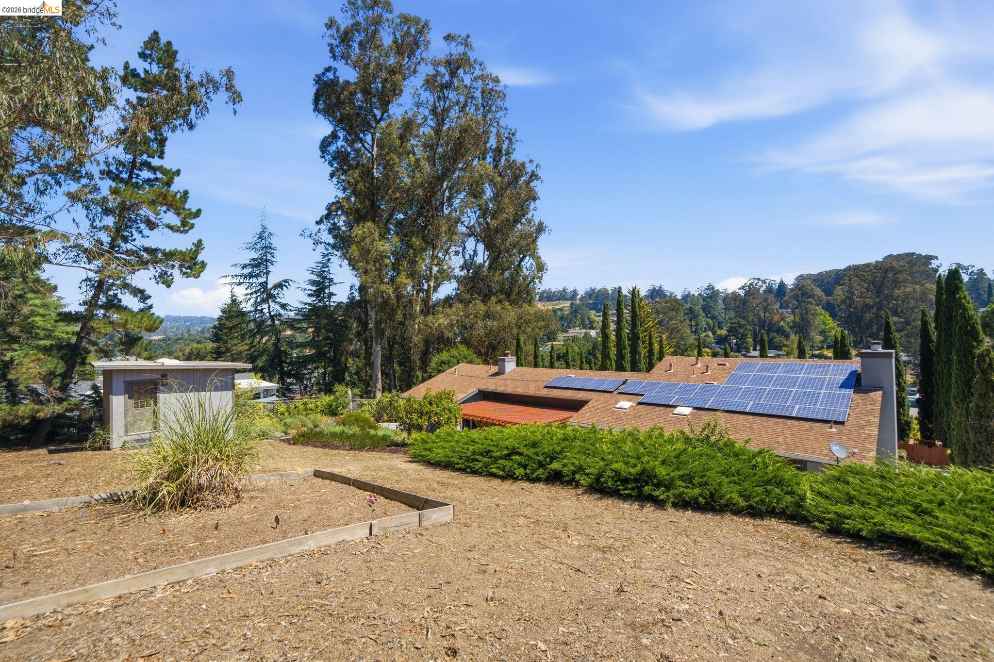 11133 Golf Links Road Oakland, CA 94605 - Photo 52 of 57 Property featuring a shingle roof, multiple solar panels, and two chimney stacks