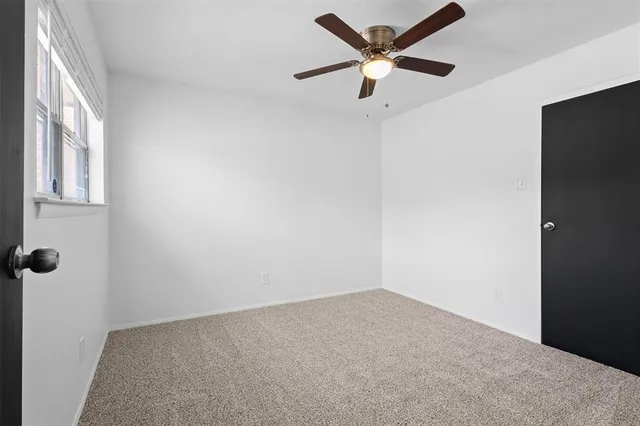 an empty room with a ceiling fan and a window