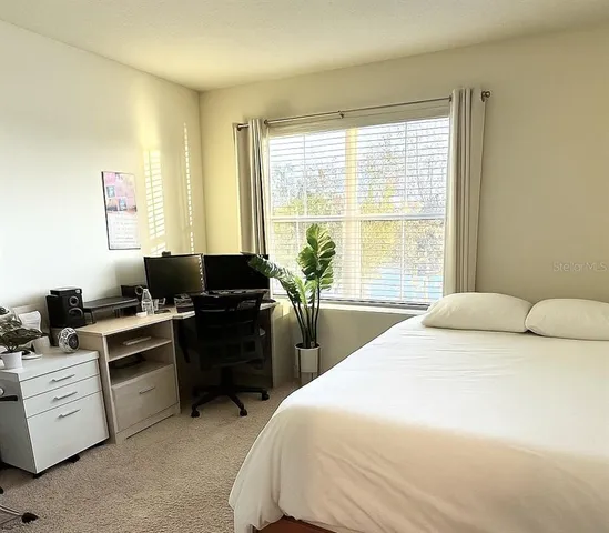 a bedroom with a bed and a computer on the desk