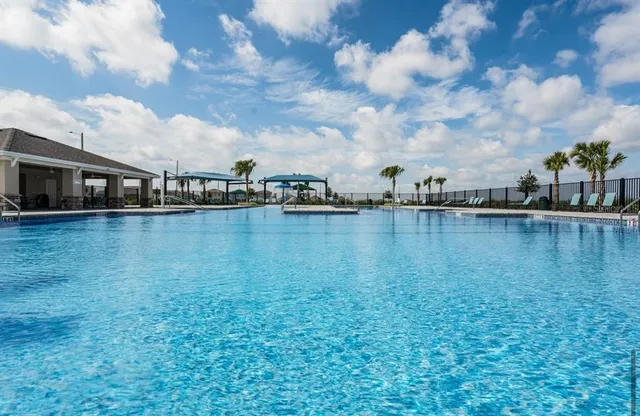 a view of a lake with lawn chairs and iron fence