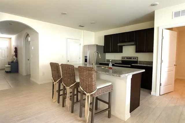 a kitchen with kitchen island granite countertop a sink cabinets and stainless steel appliances