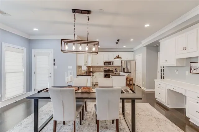 a dining room with stainless steel appliances kitchen island granite countertop a dining table chairs and a refrigerator