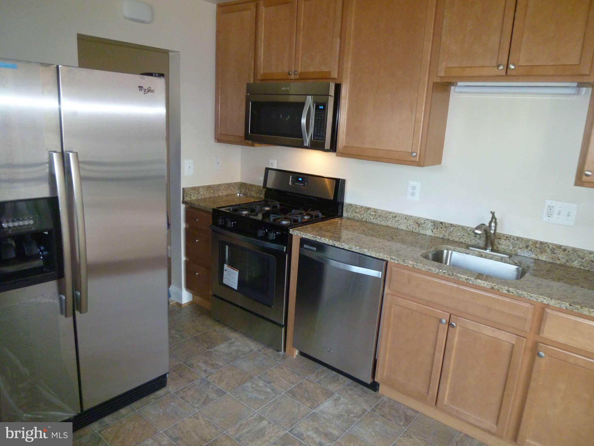 7205 Johnnycake Road Baltimore, MD 21228 - Photo 7 of 14 a kitchen with stainless steel appliances granite countertop a refrigerator a stove a sink and a microwave