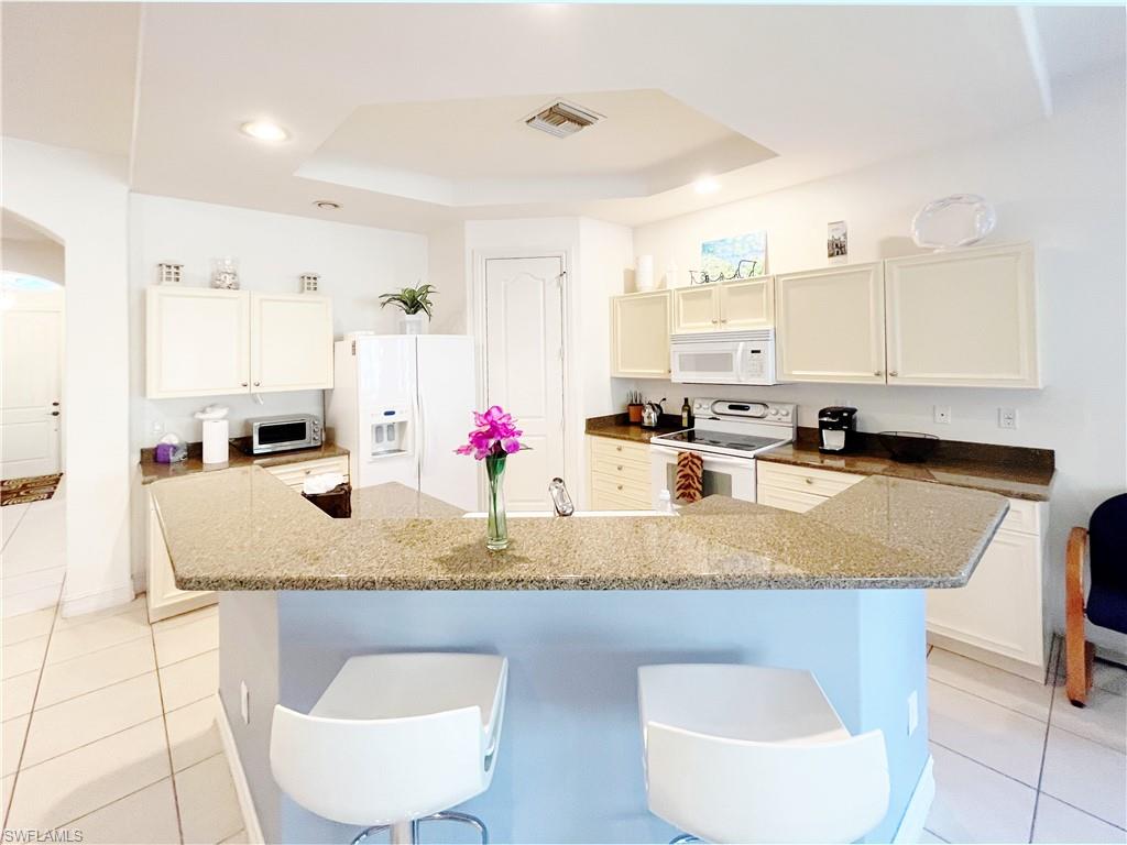 1366 Serrano Circle Naples, FL 34105 - Photo 6 of 30 a kitchen with stainless steel appliances granite countertop a sink a microwave a stove and white cabinets