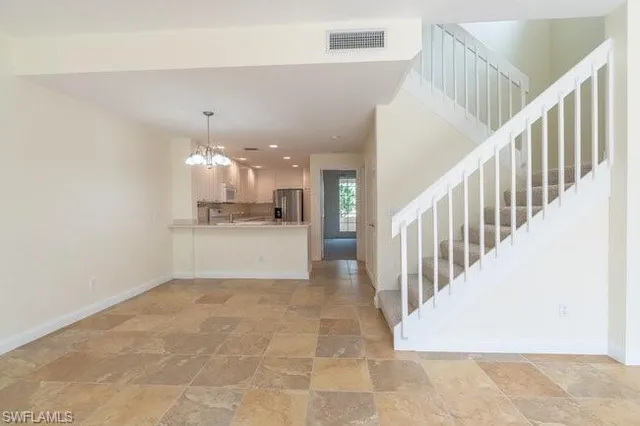 a view of a hallway with a chandelier and kitchen view
