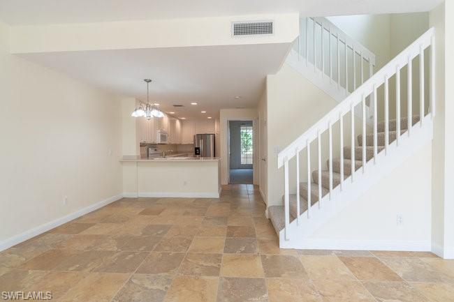 8108 Josefa Way Naples, FL 34114 - Photo 11 of 40 a view of a hallway with a chandelier and kitchen view