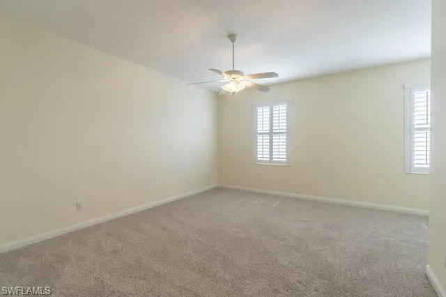 en empty room with windows and ceiling fan