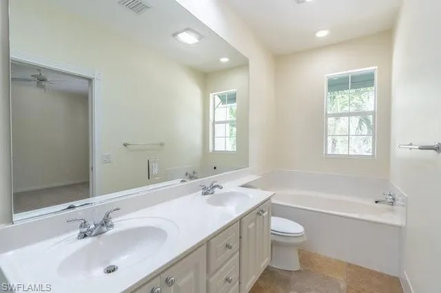a bathroom with a toilet a sink a tub and mirror