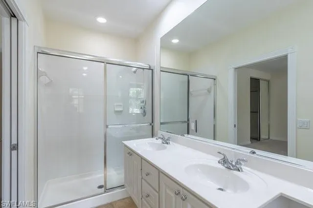 a bathroom with a double vanity sink mirror and shower
