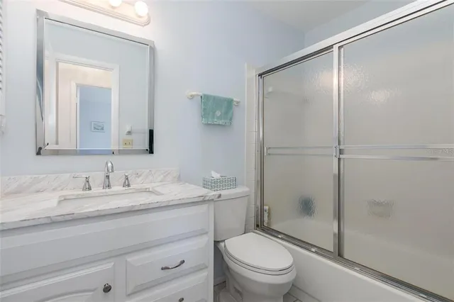 a bathroom with a shower sink vanity mirror and toilet