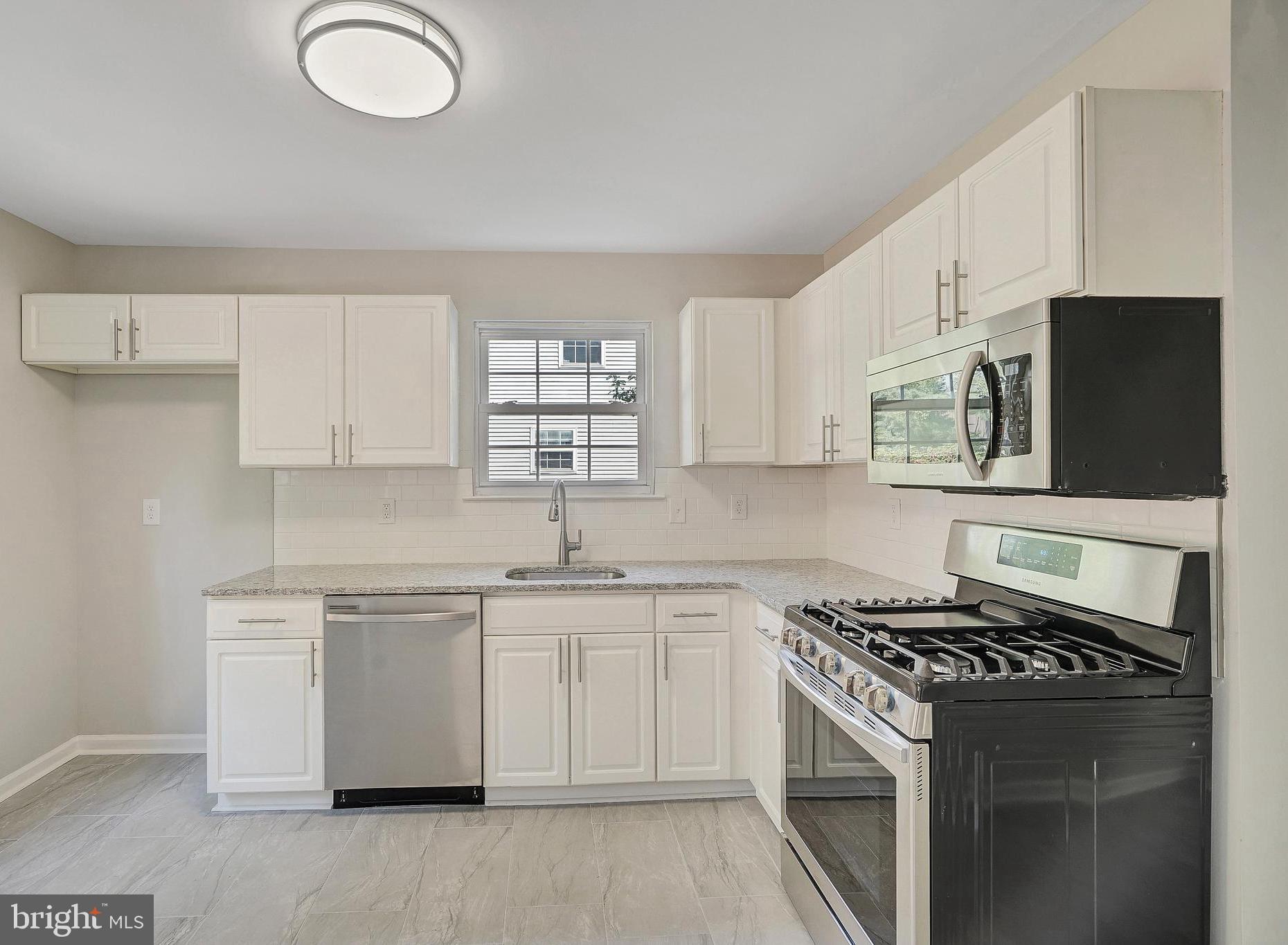 a kitchen with stainless steel appliances a sink dishwasher stove and white cabinets