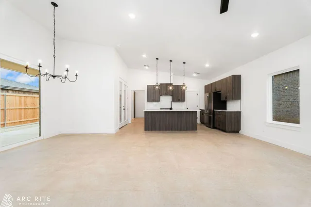 a large room with kitchen island stainless steel appliances kitchen island a large window and a refrigerator
