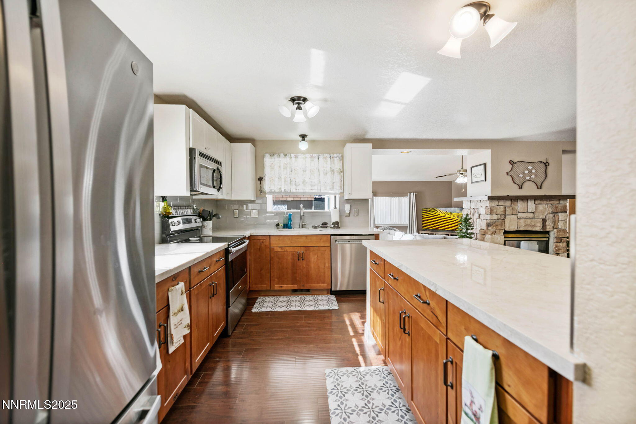 a large kitchen with stainless steel appliances granite countertop a refrigerator a sink dishwasher a stove and white countertops with wooden floor