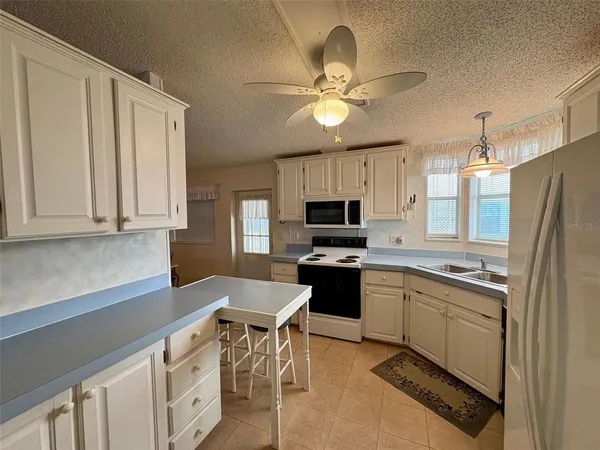 a kitchen with stainless steel appliances a sink a stove a refrigerator cabinets and furniture