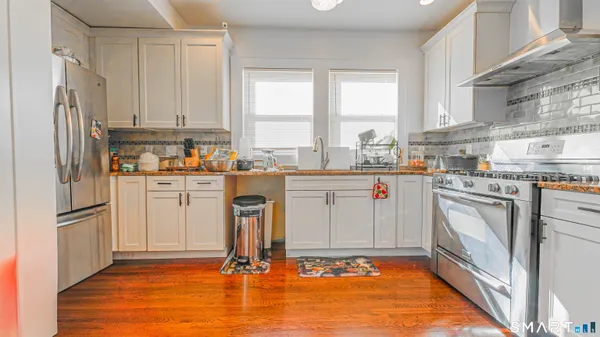 a room with stainless steel appliances granite countertop a refrigerator and a stove top oven
