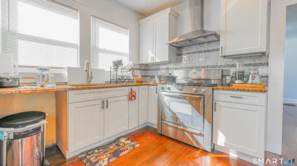 a kitchen with stainless steel appliances granite countertop a sink a stove cabinets dining table and chairs