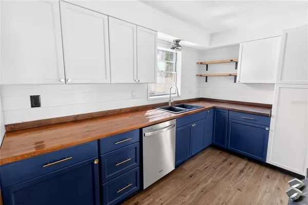 a kitchen with stainless steel appliances granite countertop a sink a stove and white cabinets with wooden floor