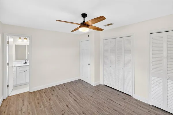 a view of empty room with wooden floor and ceiling fan