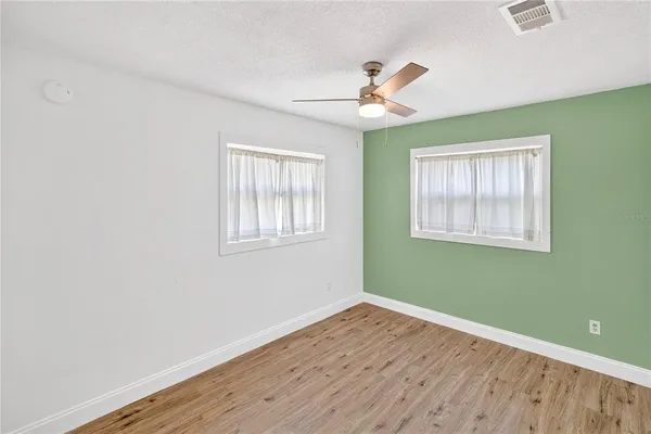 a view of a room with wooden floor ceiling fan and windows