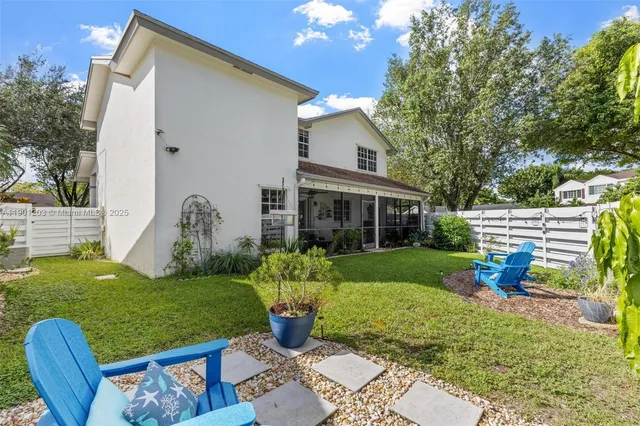 a view of a white house with a big yard and potted plants
