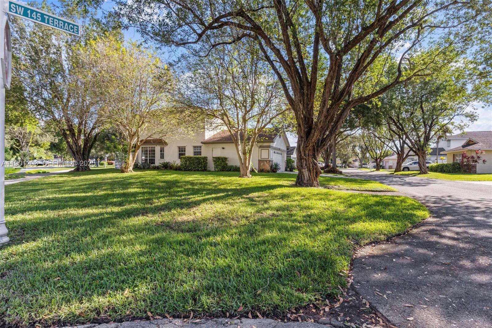 14683 Southwest 145th Terrace Miami, FL 33186 - Photo 39 of 47 a view of white house with a big yard and large trees