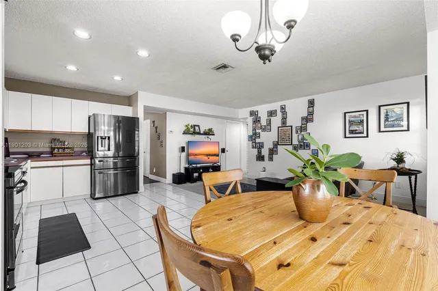 a kitchen with stainless steel appliances kitchen island granite countertop a table chairs and a refrigerator