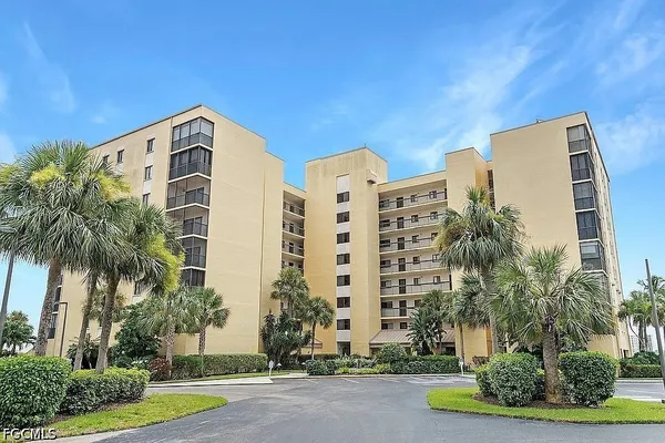 a front view of multi story residential apartment building with yard and tress in front of it
