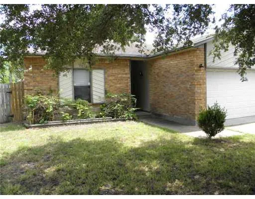 a view of yellow house with a yard and large tree